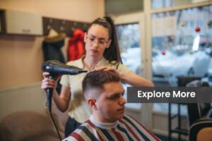 A young female hairdresser uses a hair dryer to style a man’s hairstyle